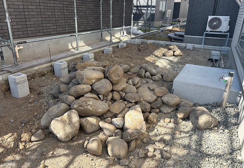 Pile of large rocks piled on a construction site near a building, with scaffolding and concrete blocks nearby.